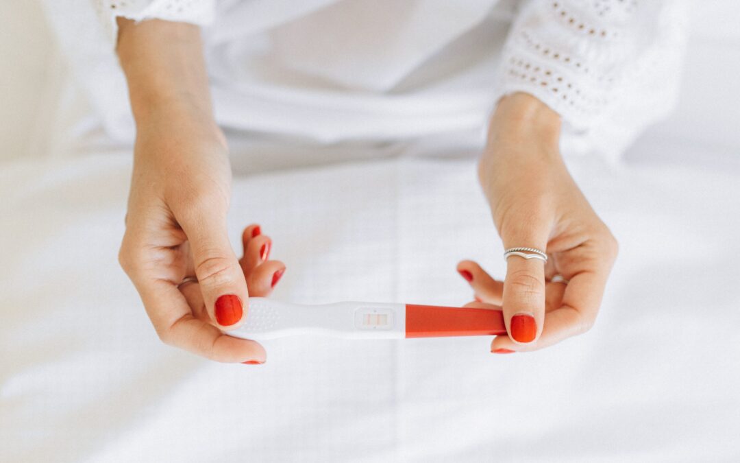 Female hands with red fingernails holds a pregnancy test