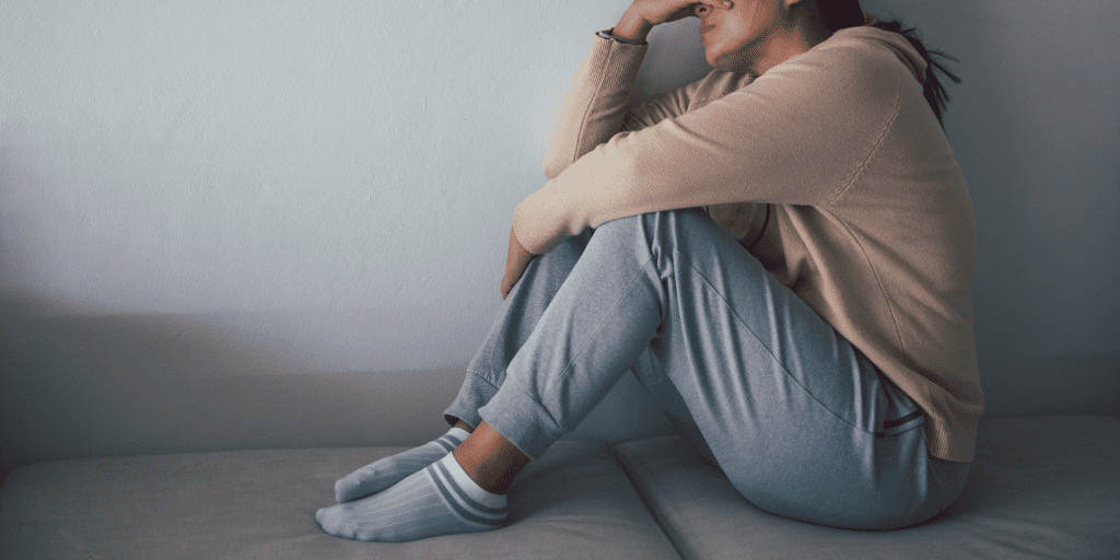 Woman sets with her head in her hand, resting her elbows on her knees