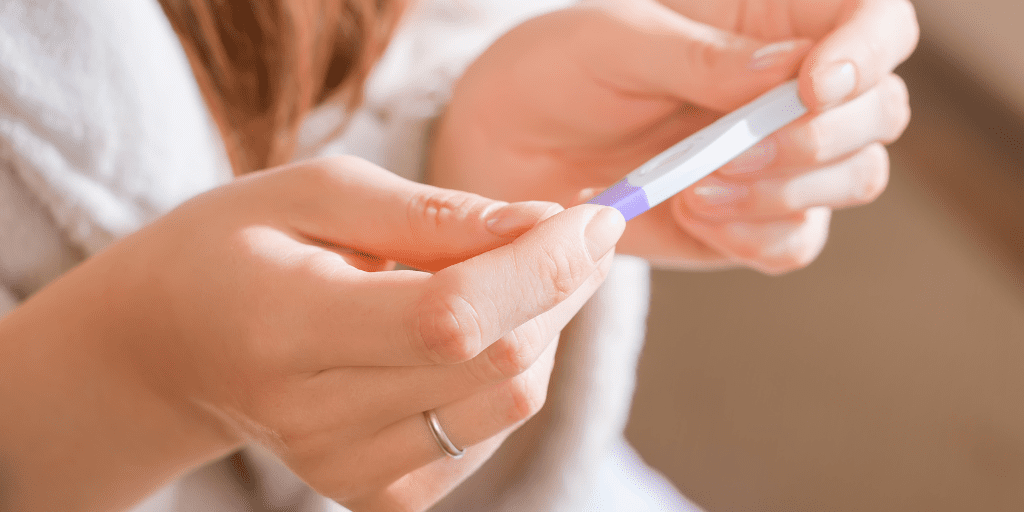 Close-up shot of female hands holding a pregnancy test, presumably positive