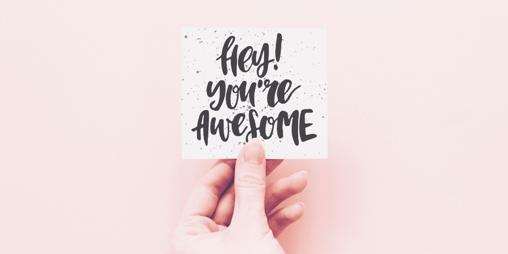 Hand holds a note that reads, "Hey! You're awesome"