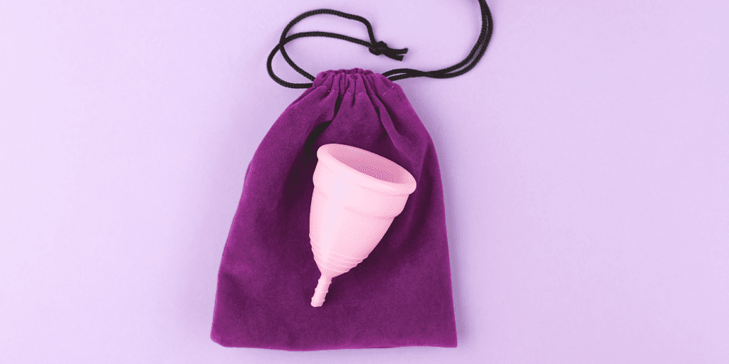 A menstrual cup is shown laying on a special carrying case for it. Some women report less period cramps with menstrual cups.