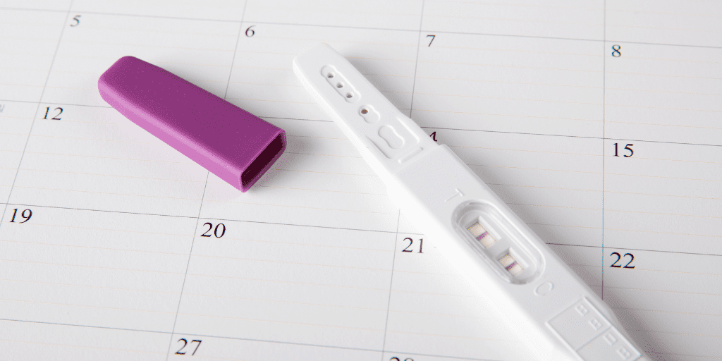 Can I get pregnant during my period? Pregnancy test laying on calendar 
